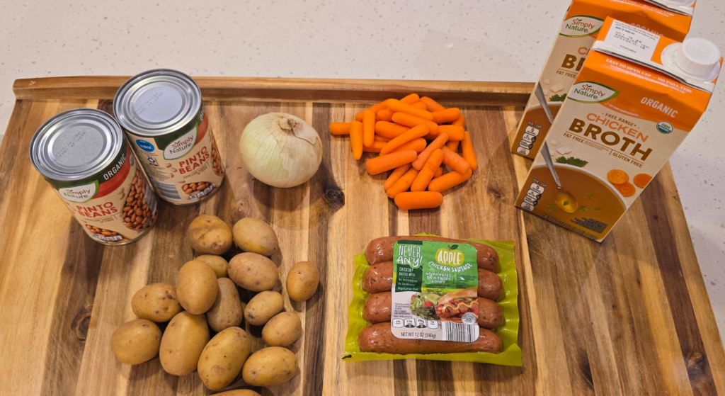 Ingredients for organic chicken sausage and bean soup arranged on a cutting board including mirepoix