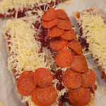 French bread pizzas on a baking sheet with melted mozzarella and pepperoni